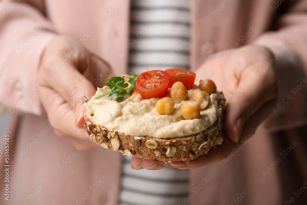 Woman holding delicious sandwich with hummus , tomato slices and chickpeas , closeup