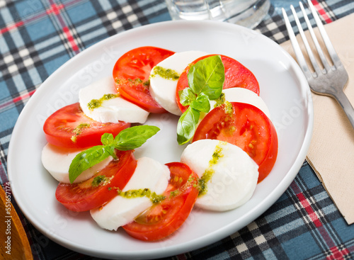 Traditional dish of Italian cuisine caprese salad with fresh tomatoes and mozzarella cheese at plate