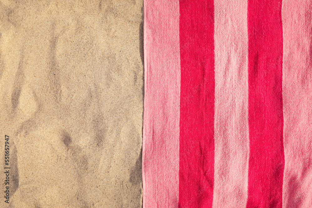 Fototapeta premium Soft pink beach towel on sand, top view. Space for text