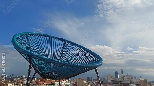 Silla de reposo en terraza bajo el sol con nubes en Barcelona