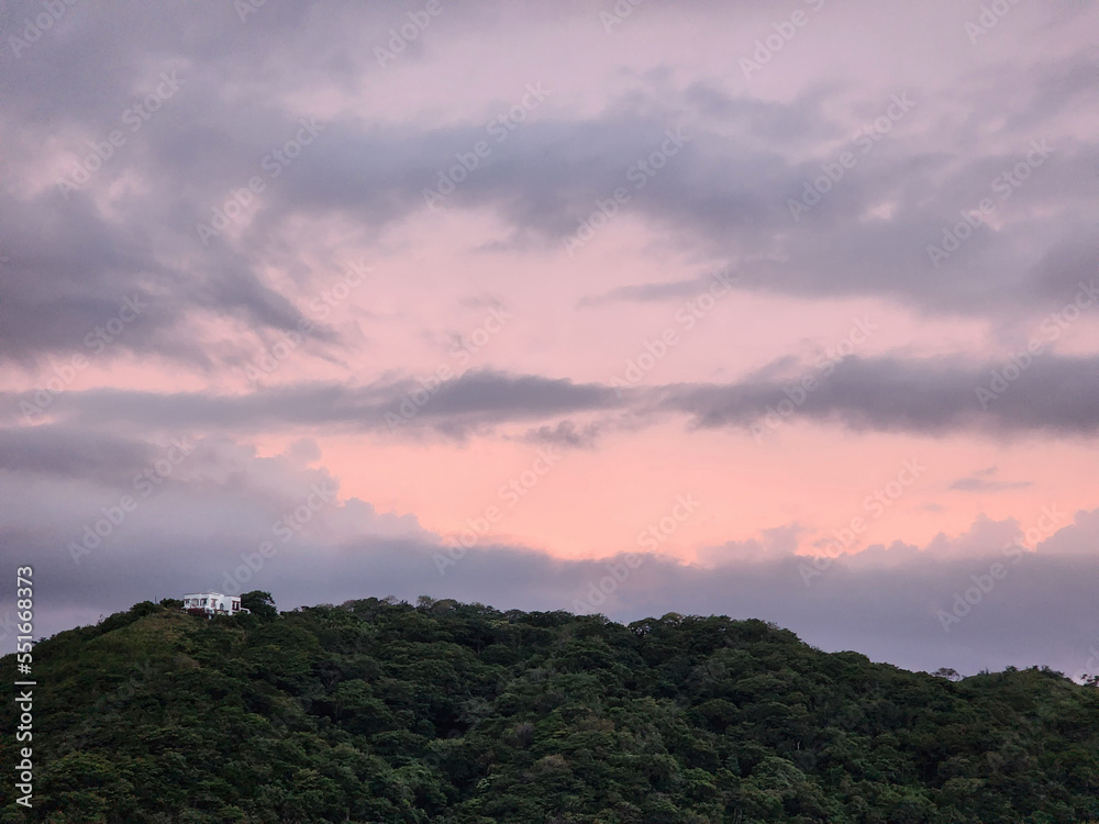 Pink  sunset over green hill with house