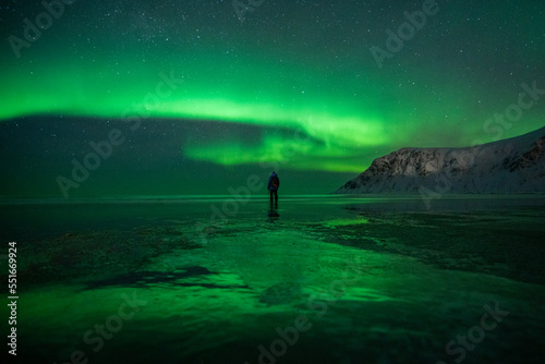 Man watching Northern Lights on a beach in Northern Norway