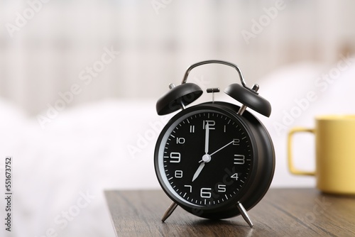 Black alarm clock on wooden table indoors. Space for text