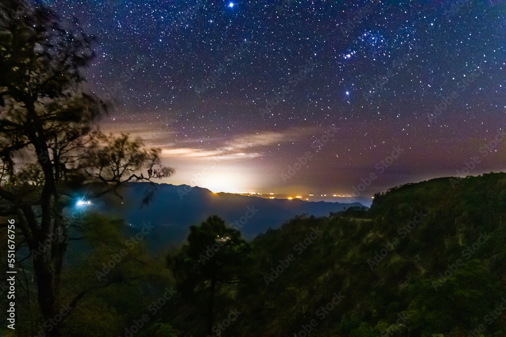 forest at night with bright lights in the background, and  sky full of stars, view of mazatlan from mountains in mexiquillo durango