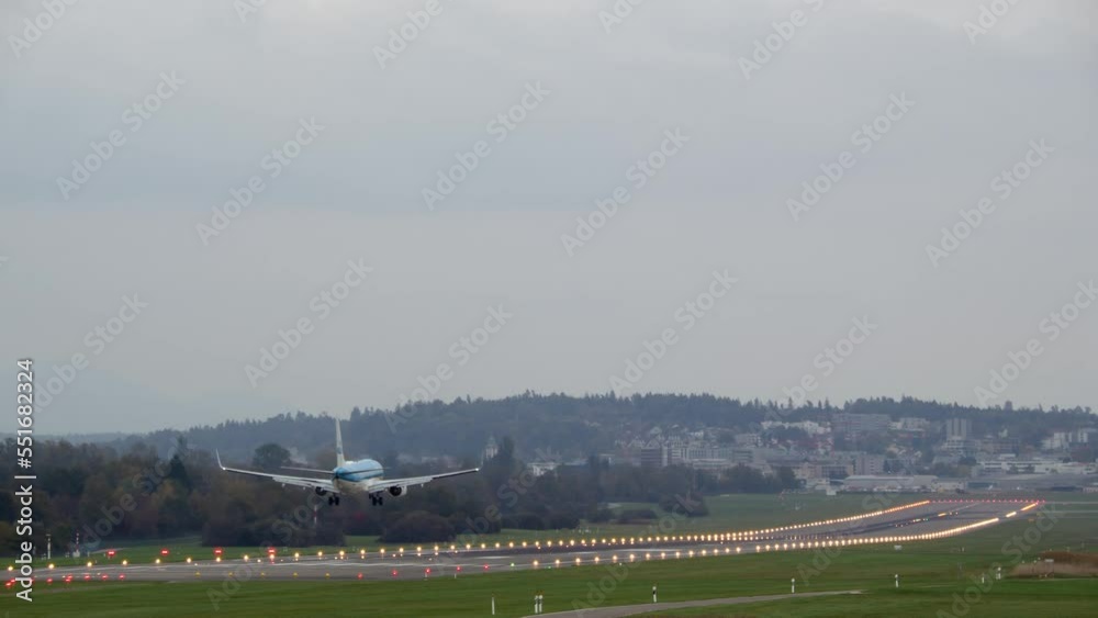 A passenger airplane in a blue livery landed at the airport on a brightly lit runway A passenger airplane in a blue livery landed at the airport on a brightly lit runway