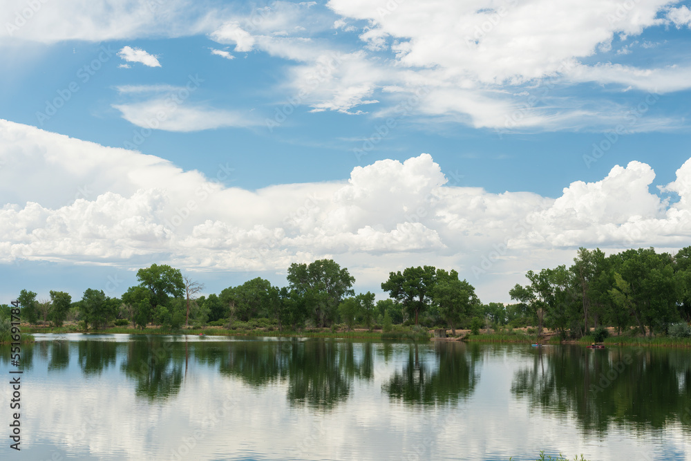 Fototapeta premium Reflections of clouds and trees in a still lake.