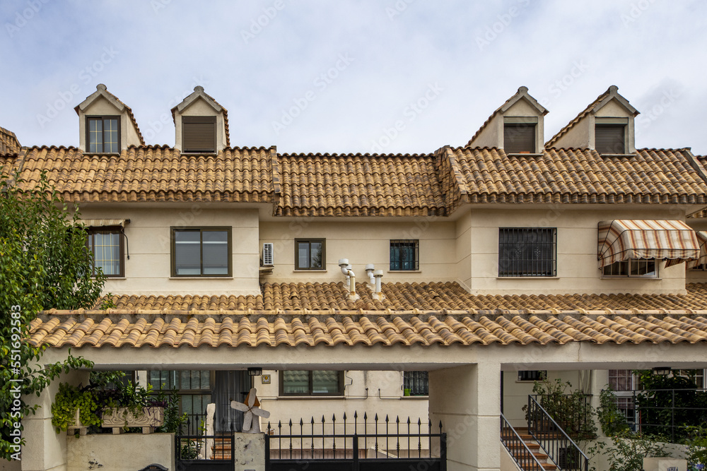 Urbanization with two-story houses with patios and common areas with mud roofs, attics with windows, metal gates and access stairs Urbanization with two-story houses with patios and common areas with mud roofs, attics with windows, metal gates and access stairs
