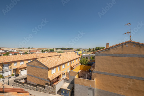 Urbanization with two-story houses with patios and common areas with clay roofs in the middle of the field