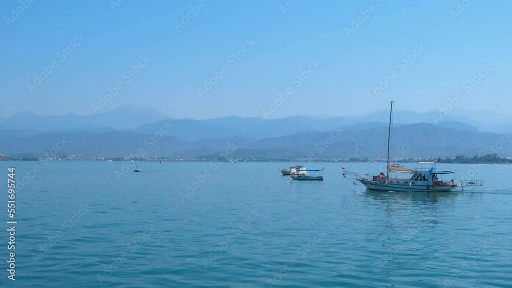 Pleasure yachts floating in moorage. A view of pleasure floating with modern yachts against blue sea water in summer. A concept of summer tourism by sea. Pleasure yachts floating in moorage. A view of pleasure floating with modern yachts against blue sea water in summer. A concept of summer tourism by sea.