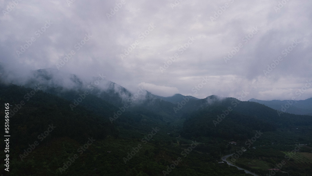 Aerial view of tropical forest with mist in the morning. Top view from drone of beautiful mountain tropical forest during winter in Thailand. Natural landscape background.