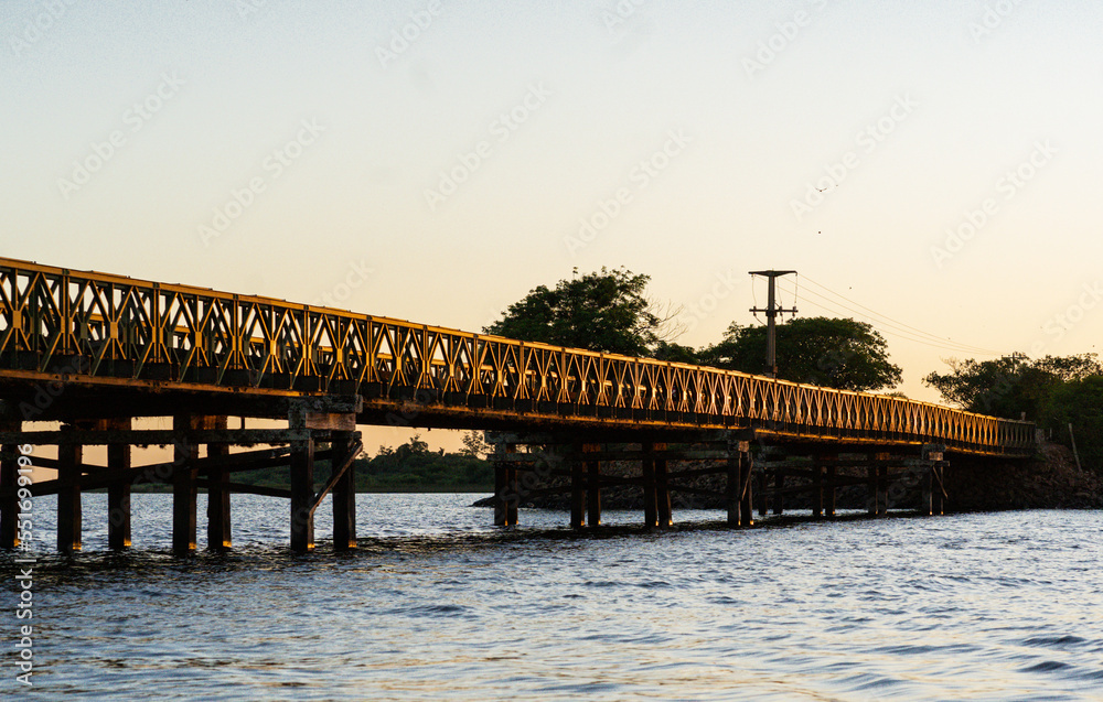 Beautiful landscape with an old iron and wooden bridge and a river during sunset in Colonia Carlos Pellegrini, Iberá Wetlands, Provincial Park, Corrientes, Argentina.