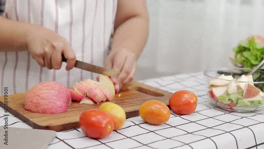 Asian woman cooking in kitchen and chopping apple on chopping board. Learn to make salads and healthy food from social media. health care concept Eat healthy food to lose weight Asian woman cooking in kitchen and chopping apple on chopping board. Learn to make salads and healthy food from social media. health care concept Eat healthy food to lose weight