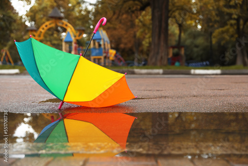 Colorful umbrella near puddle outdoors, space for text © New Africa