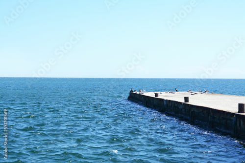 Beautiful concrete pier in sea on sunny day, space for text
