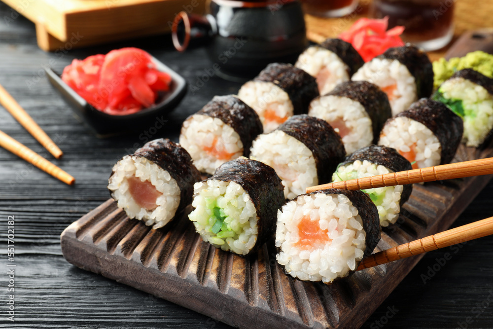 Set of delicious sushi rolls and chopsticks on black wooden table, closeup Set of delicious sushi rolls and chopsticks on black wooden table, closeup