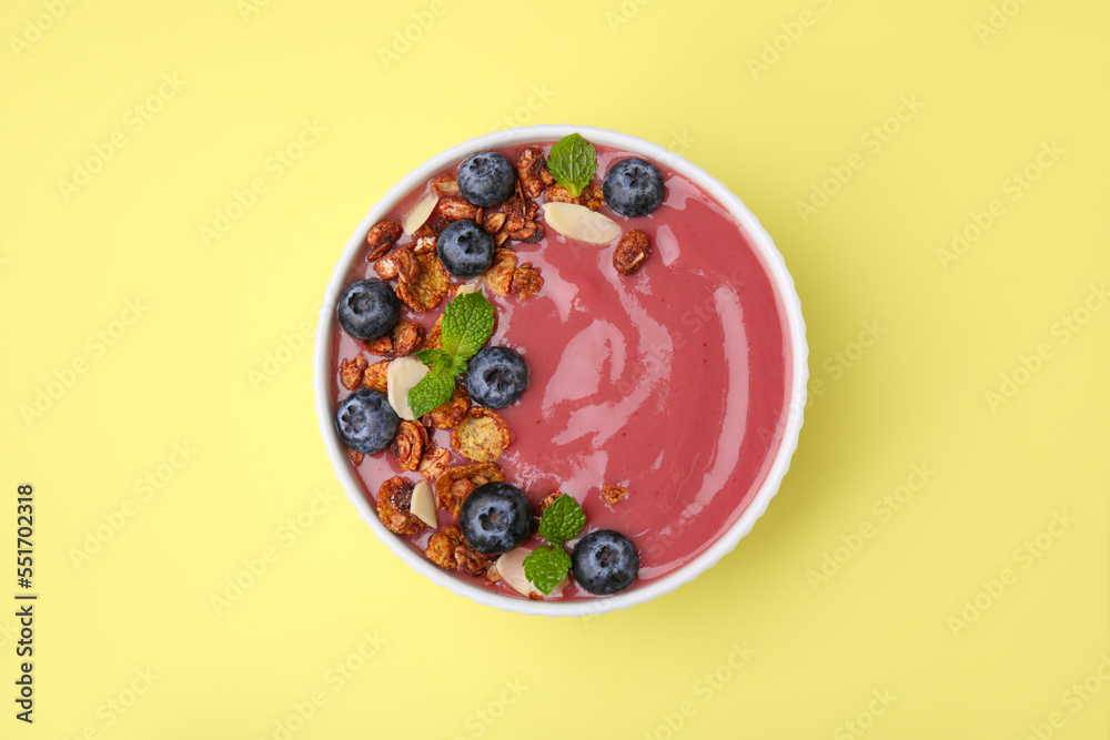 Bowl of delicious smoothie with fresh blueberries and granola on yellow background, top view Bowl of delicious smoothie with fresh blueberries and granola on yellow background, top view