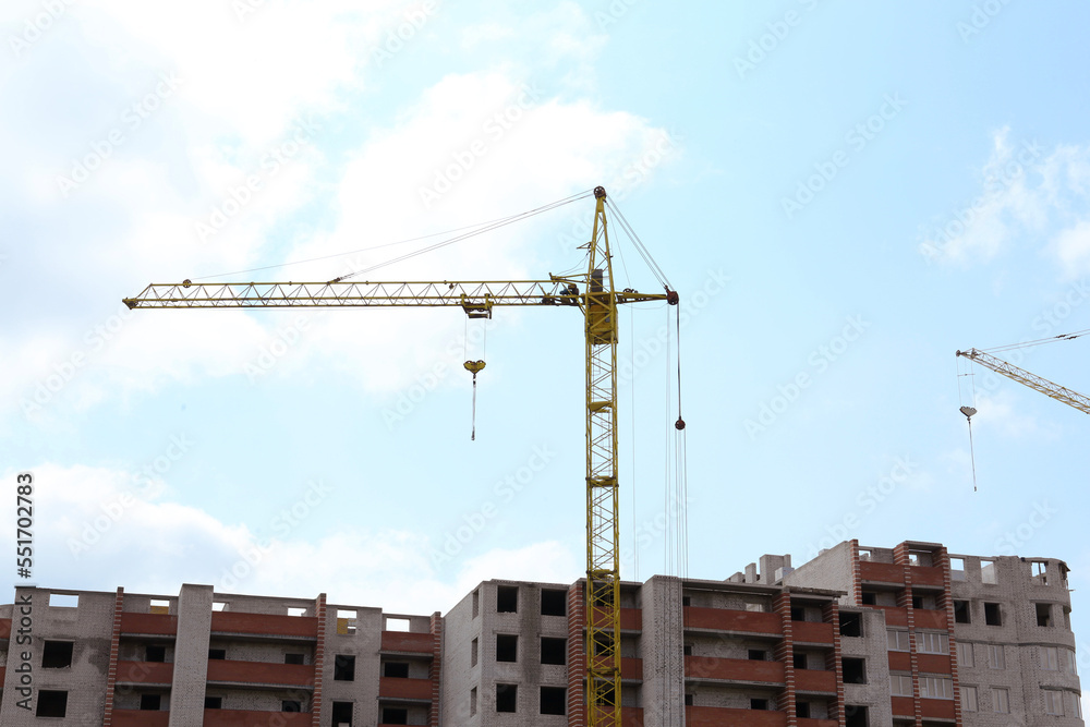 Construction site with tower crane near unfinished building