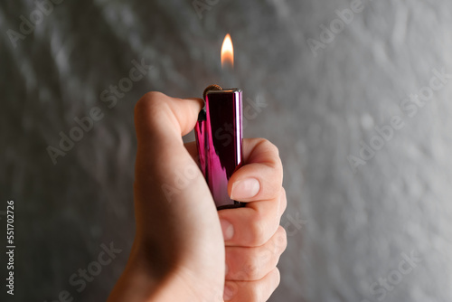 Woman holding pink lighter on grey background, closeup