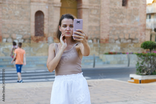 A young stylish woman communicates on a smartphone on a city street © Enigma