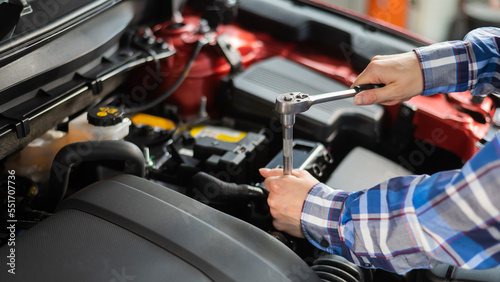 Female auto mechanic unscrewing a nut to replace a car spark plug. © Михаил Решетников