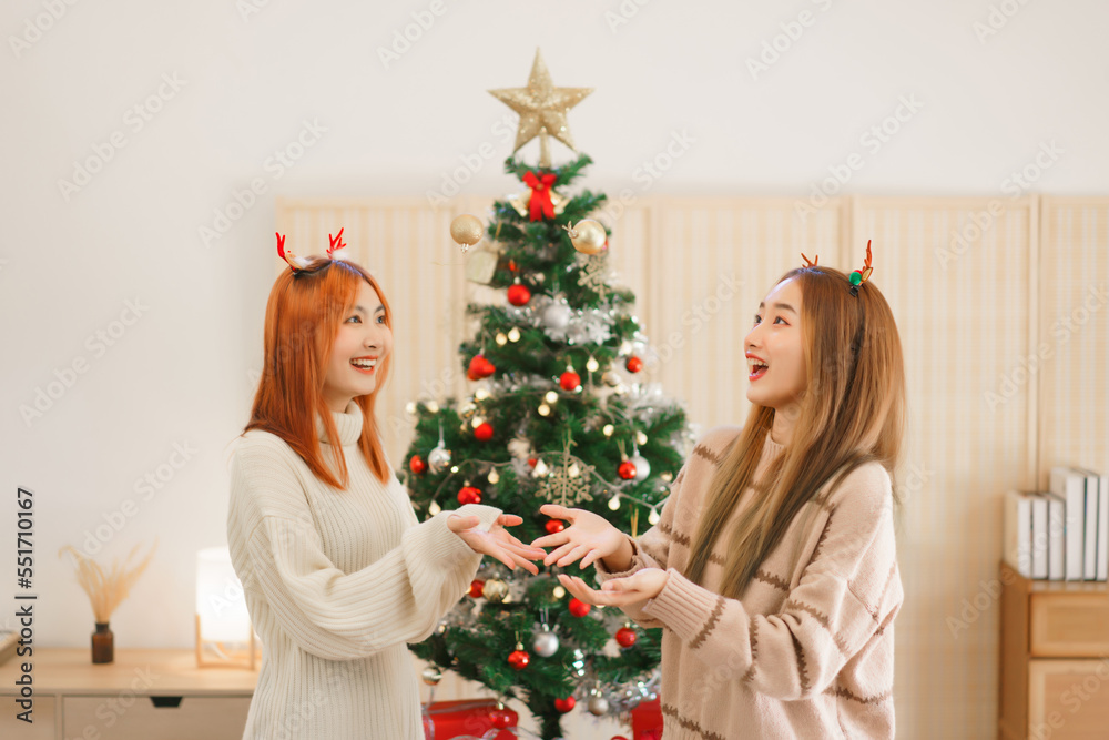 Christmas festive concept, Two women wears reindeer horns and throwing christmas ball with have fun