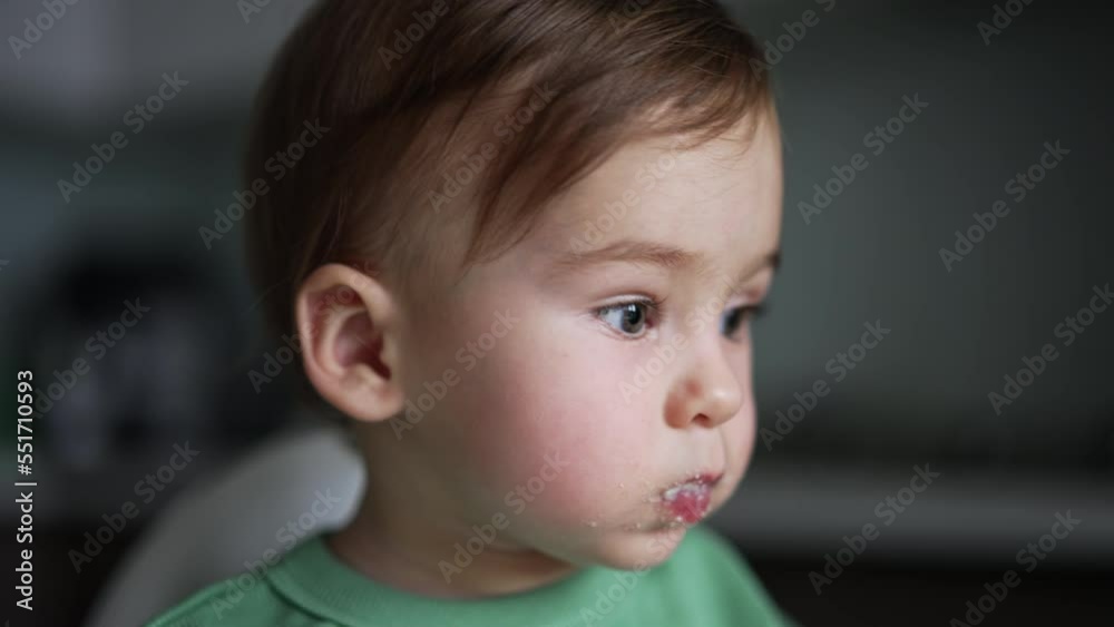Small kid sitting on table and having breakfast. Portrait of cute baby eating.