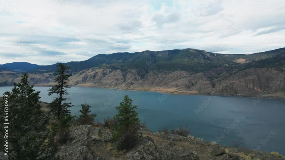 Approaching Aerial shot over the Rocky Cliffs of Kamloops Lake flying towards Evergreen covered Mountains Approaching Aerial shot over the Rocky Cliffs of Kamloops Lake flying towards Evergreen covered Mountains