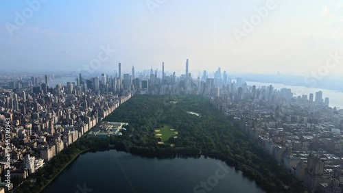 Slowmotion Aerial of Central Park. Deep green forest in the middle of Manhattan, beautiful aerial perspective of the Lake and skyline fading in the background. photo