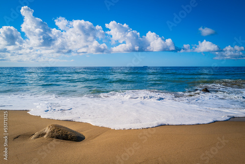 Tranquil Zen-like seascape of Zuma Beach, Malibu, California, with white rocks, waves rolling in on the clean sand, and white clouds over the blue horizon photo