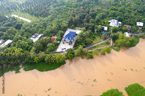 aerial view of Villa house in the middle of the garden with blue tile roof and the river at Mekong river delta VietNam countryside, Thai house building style. 