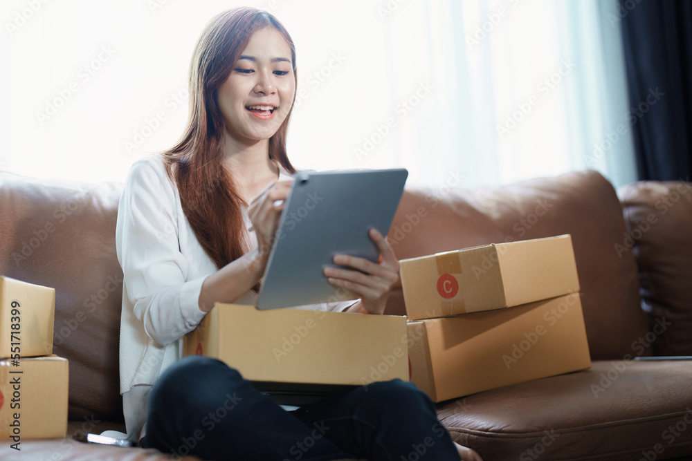 Starting small business entrepreneur of independent young Asian woman online seller is using tablet computer and taking orders to pack products for delivery to customers. SME delivery concept Starting small business entrepreneur of independent young Asian woman online seller is using tablet computer and taking orders to pack products for delivery to customers. SME delivery concept