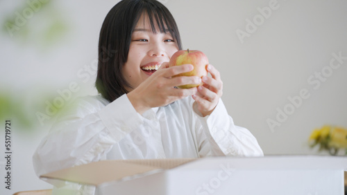 ダンボールからりんごを取り出す女性（通販・お取り寄せグルメ）