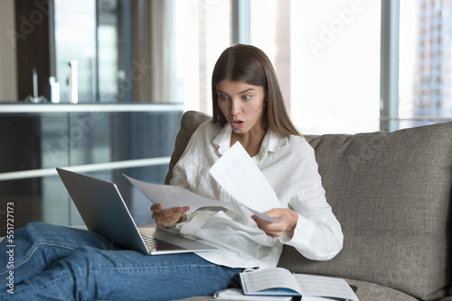 Shocked concerned young freelance employee reading paper notification with bad news, getting problems, rejection, dismissal, bankruptcy. Student girl receiving document from college
