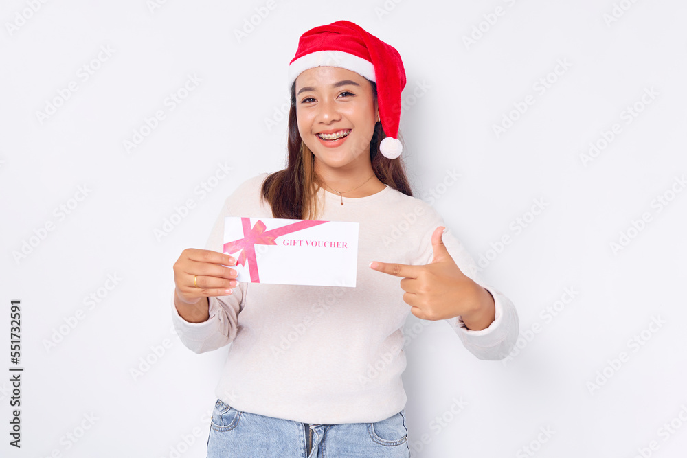 Smiling young Asian woman 20s in hat Christmas Pointing finger at a gift certificate coupon voucher card isolated on white studio background. Merry Christmas Concept Smiling young Asian woman 20s in hat Christmas Pointing finger at a gift certificate coupon voucher card isolated on white studio background. Merry Christmas Concept