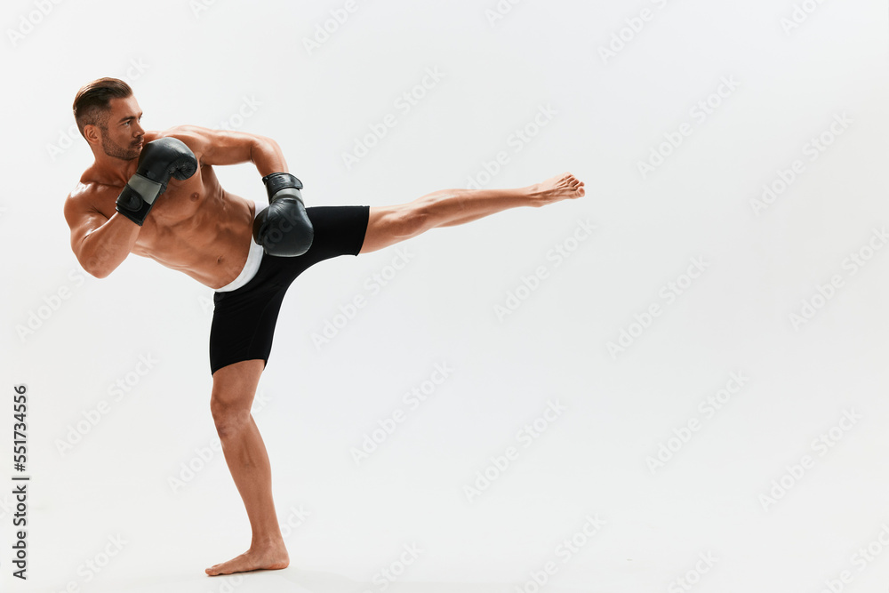 Man athletic bodybuilder poses in boxing gloves with nude torso abs in full-length background, boxing and martial arts. Advertising, sports, active lifestyle, light, competition, challenge concept. 