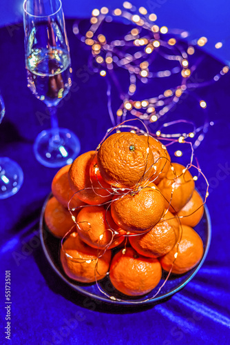 Christmas and New Year concept. Tangerines and champagne on a blue velvet background at a party, close up
