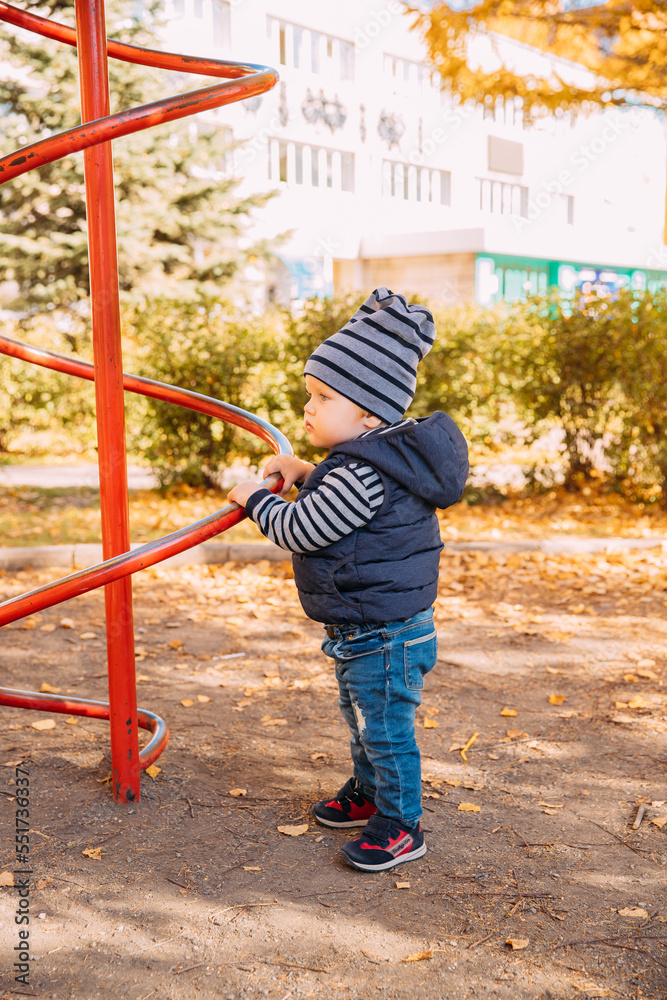 A cute little boy plays on the playground in the fall A cute little boy plays on the playground in the fall