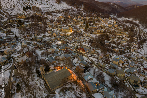 Aerial view of traditional architecture  with  stone buildings and the famous local school with a label in front. tranlation Nikios(name ) school in the snowy village of Nymfaio  Florinas Greece © valantis minogiannis