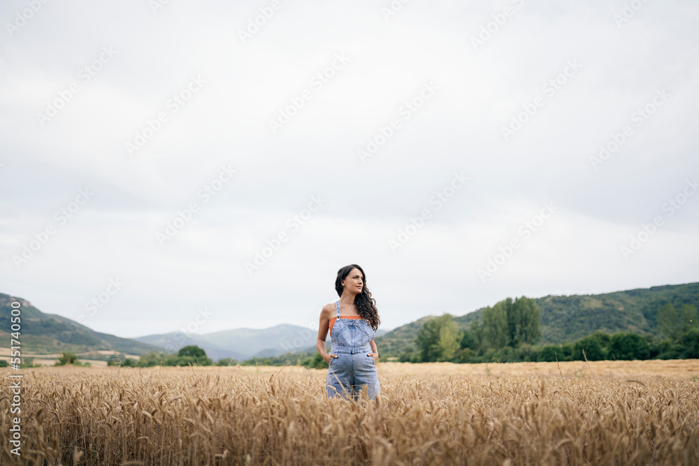 Pregnant young woman in wheat field smiling and calmed