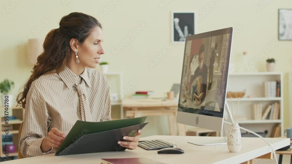 Confident young brunette businesswoman having online video meeting with office team on computer while working from home Confident young brunette businesswoman having online video meeting with office team on computer while working from home