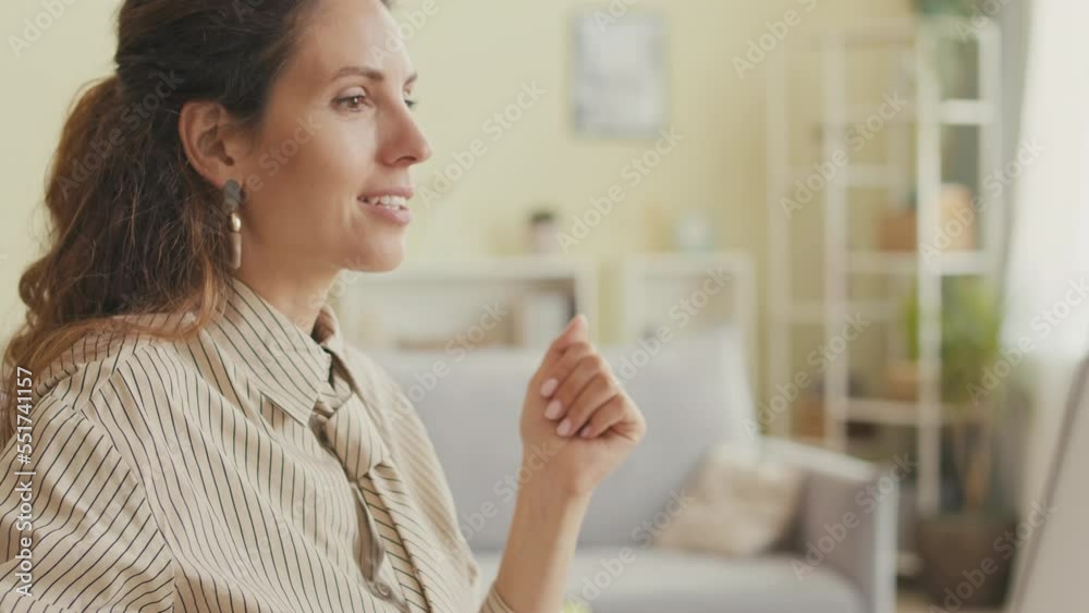 Young successful businesswoman with confident smile using smartphone and typing on computer while working from home office Young successful businesswoman with confident smile using smartphone and typing on computer while working from home office