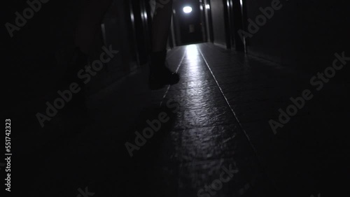 a girl in coarse boots with untied laces runs along a dark corridor. back view