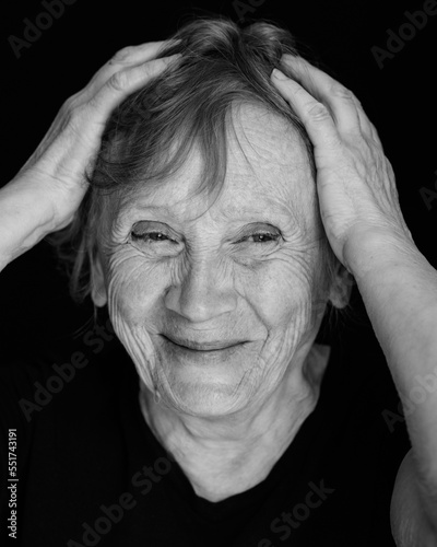 Portrait of senior smiling caucasian woman with hand on head on black background