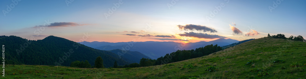 panorama of svydovets ridge at sunset. beautiful summer landscape of carpathian mountains. grassy meadows and forest on the hill. clouds on the sky