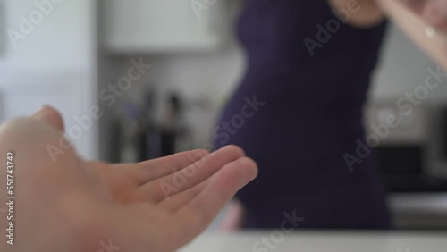 Pregnant woman taking meds or vitamins in kitchen and drinking water. Health and wellbeing in third trimester. Pregnant with belly.