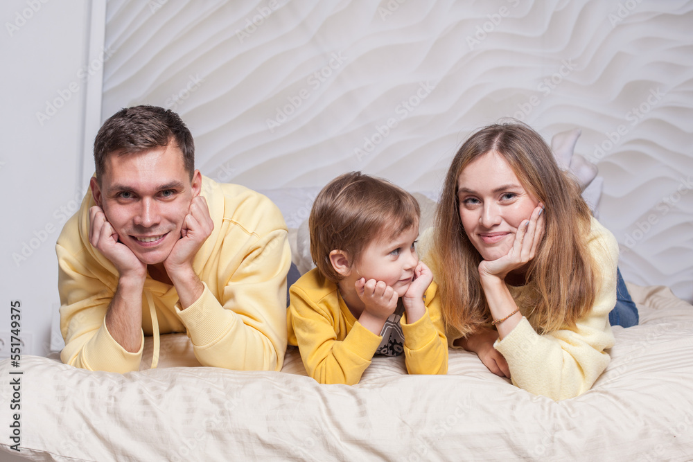 Portrait of lovely family, parents, mom and dad with adorable child son on the bed Portrait of lovely family, parents, mom and dad with adorable child son on the bed