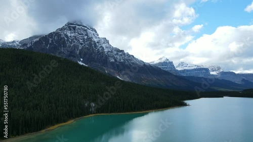 Scenic Cinematographic view of Mountains with snow peaks and pine woods in Banff National Park on a sunny day. Lake with turquoise water.Green autumn forest in the Rocky Mountains in Canada.