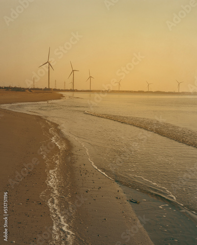 Offshore windmills with morning sky, windmill park in the ocean view of wind turbine beach. Green energy. 