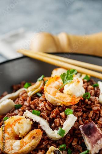 delicious red rice with shrimps and seafood on a gray stone background