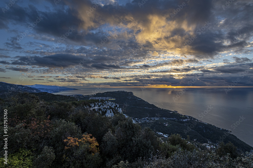 Panorama en bord de mer sur la Côte d'Azur avec comme paysage un ciel menaçant et un coucher de soleil et des falaises